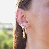 Side of Burdlife Model's head displaying 3 earrings including the Luxe Oval Hoops, the Refined Single Chain Earring and the Modish Triple Crystal Studs. 