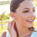 Burdlife model displaying 3 earrings including the Luxe Oval Hoops, the Refined Single Chain Earring and the Modish Triple Crystal Studs. 