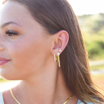 Side of Burdlife Model's head displaying 3 earrings including the Luxe Oval Hoops, the Refined Single Chain Earring and the Modish Triple Crystal Studs. 