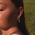 Side of Burdlife Model's head displaying 3 earrings including the Luxe Oval Hoops, the Refined Single Chain Earring and the Modish Triple Crystal Studs. 