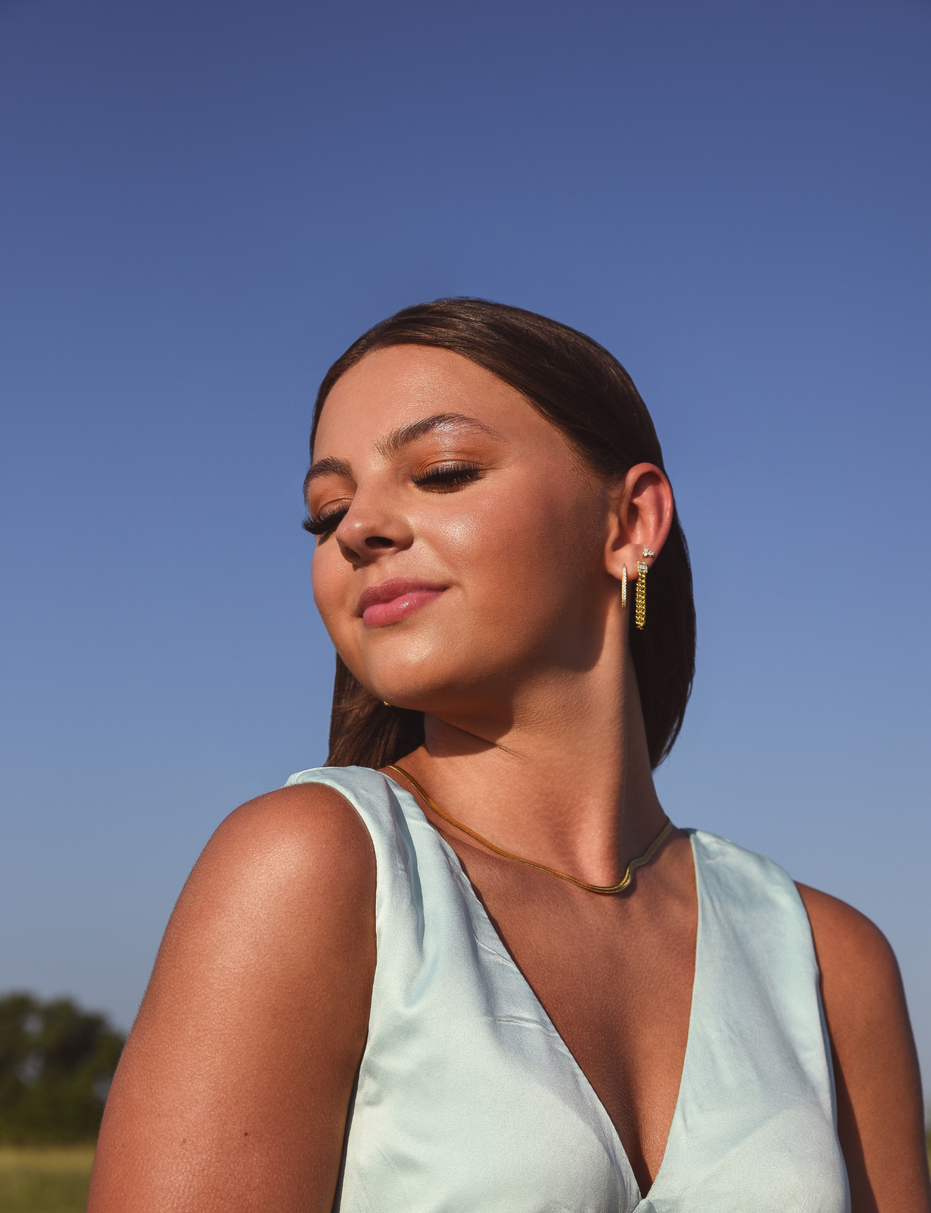 Model wearing 3 earrings including the Luxe Oval Hoops, the Refined Single Chain Earring and the Modish Triple Crystal Studs. 